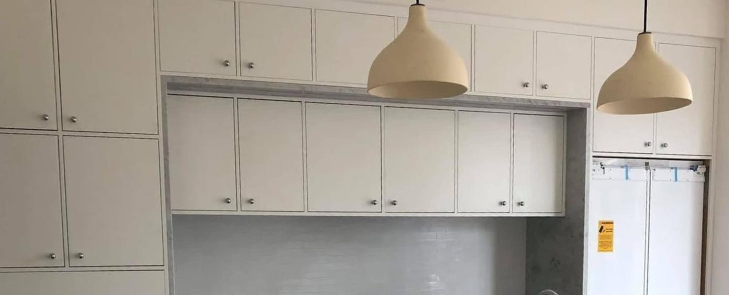 Custom floor-to-ceiling white shaker cabinets featuring minimalist hardware and a clean, seamless finish by MG Contractor NY